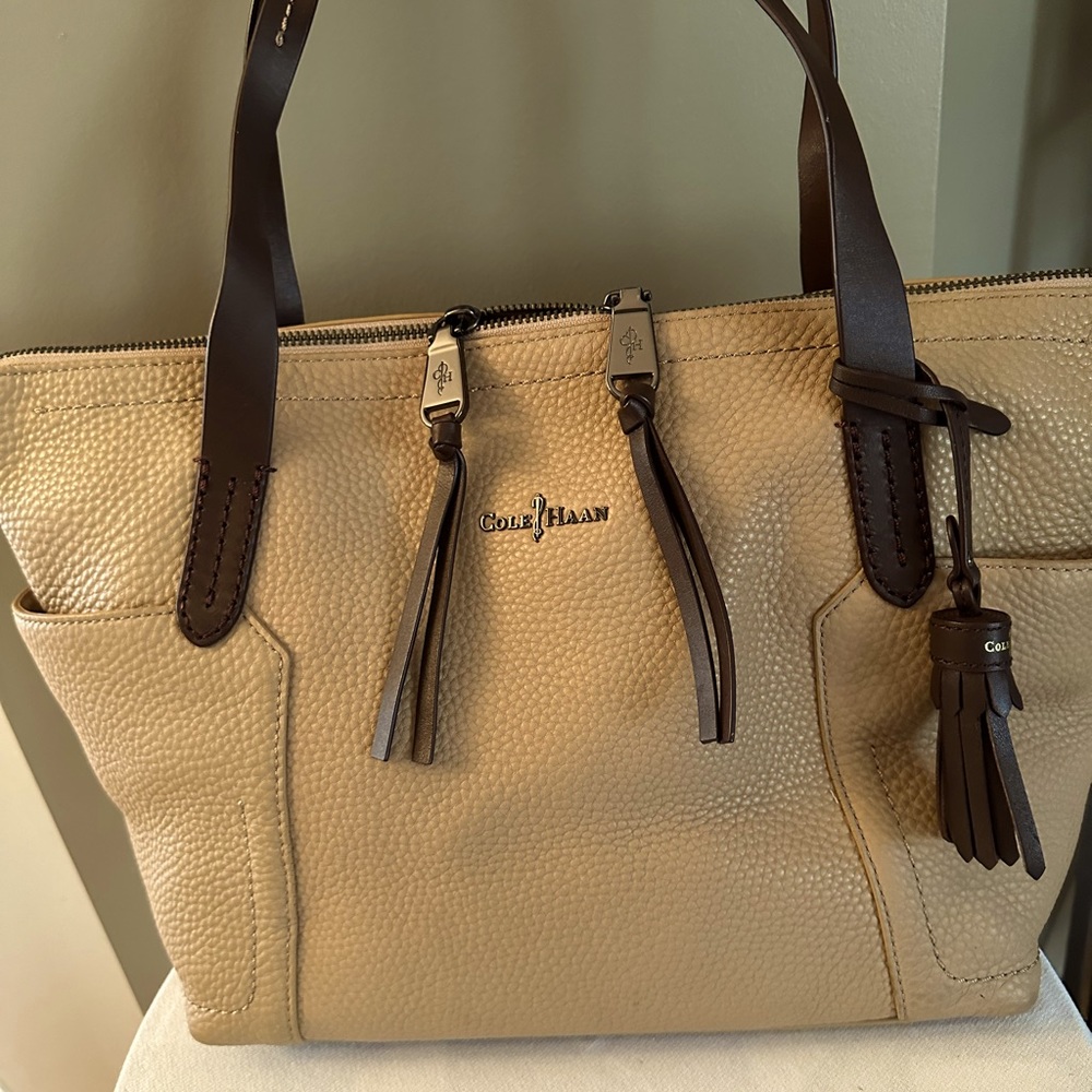 Tan leather tote with brown leather straps and tassels.